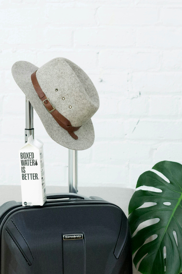 A suitcase with a hat hanging on the handle