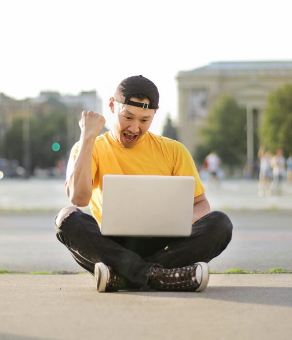 Student making a gesture of joy in front of a laptop