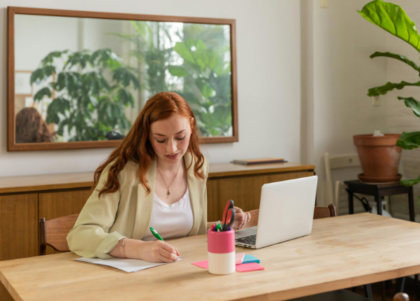 Female student taking notes in front of a laptop